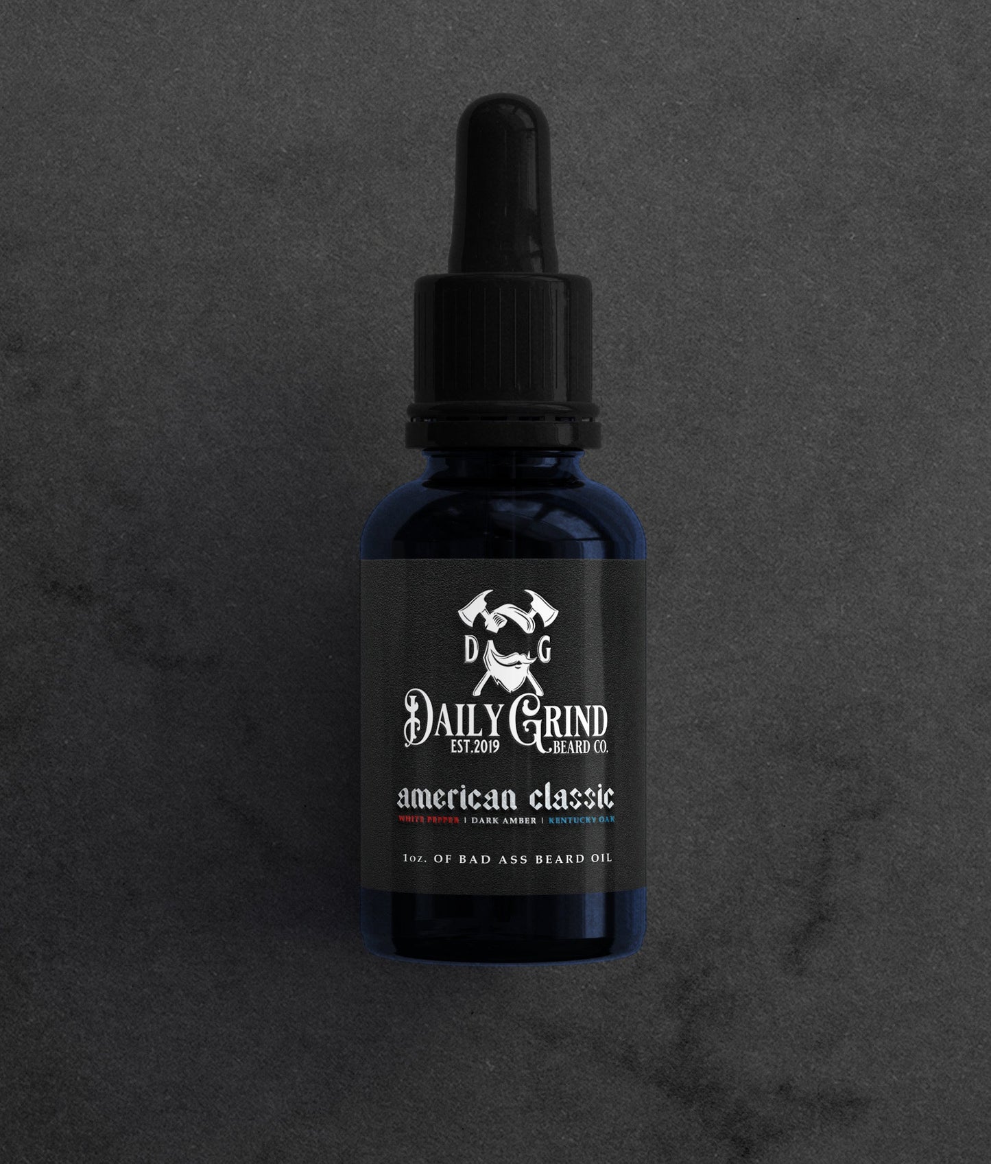 American Classic white pepper dark amber Kentucky oak beard oil for men by Daily Grind in a blue bottle on a dark stone background