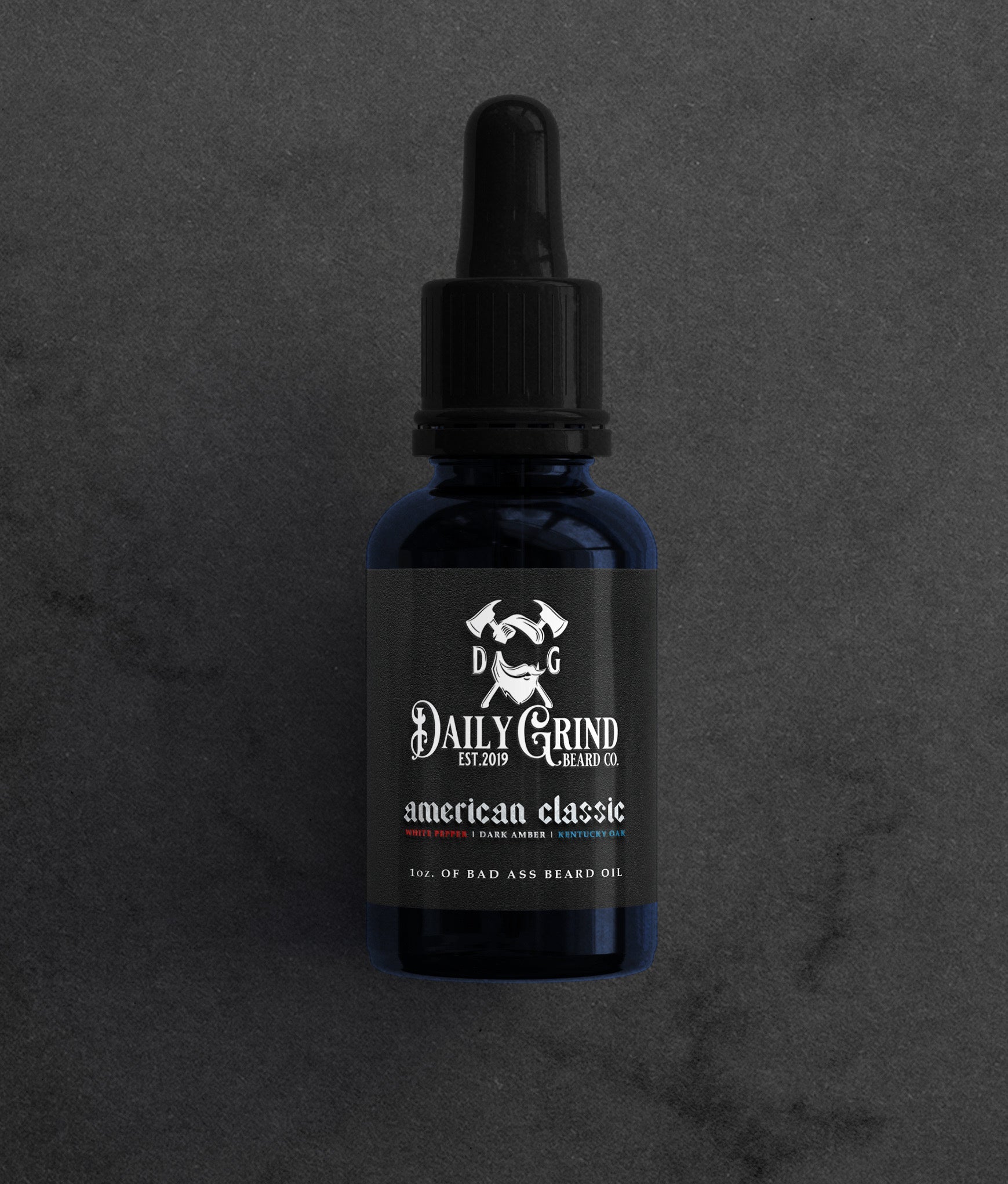 American Classic white pepper dark amber Kentucky oak beard oil for men by Daily Grind in a blue bottle on a dark stone background