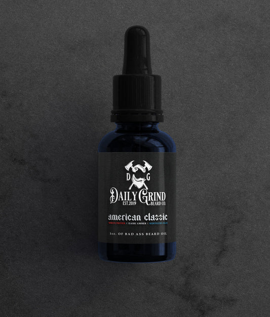 American Classic white pepper dark amber Kentucky oak beard oil for men by Daily Grind in a blue bottle on a dark stone background