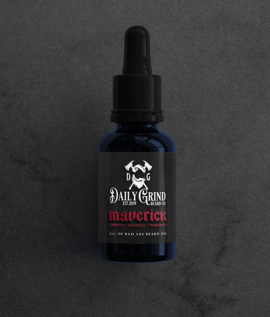 Dark blue glass bottle of Daily Grind Maverick Beard Oil (Cherry Vanilla Tobacco scent) with dropper top on a textured background.